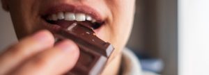 Person biting into chocolate bar