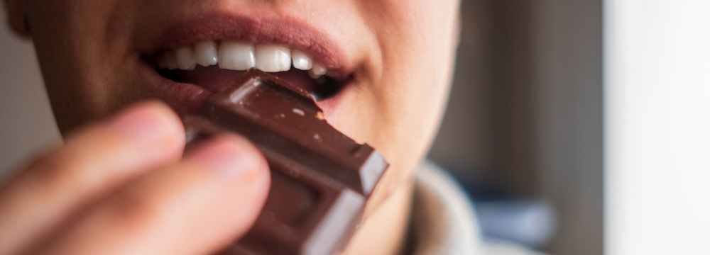 Person biting into chocolate bar 