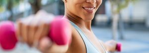 Woman strength training outdoors with pink dumbbell weights