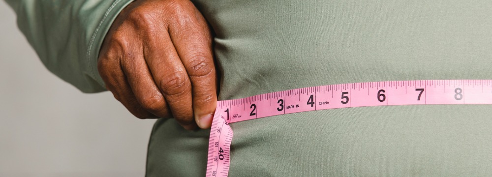 Person holding pink measuring tape to waistline to measure 