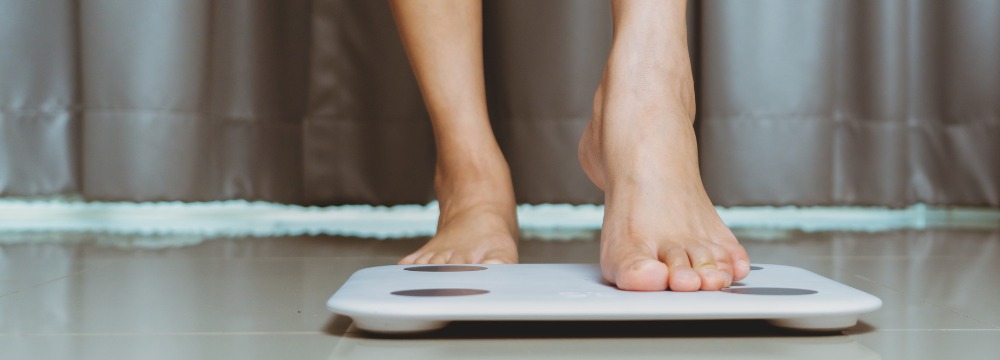 Woman stepping on scale on hard floor 