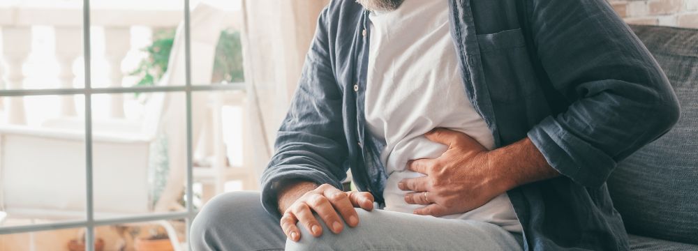 Man suffering from acid reflux holding stomach in pain 