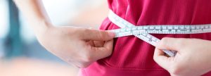 Woman measuring waist size with measuring tape